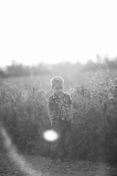 A funny young boy with eye misalignment, smiling and giggling in a sunset-lit Stock Photos