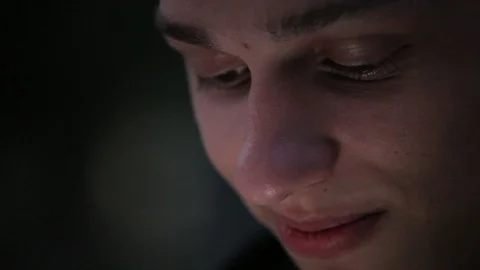 Funny young face closeup, man uses smartphone at night 库存影片 96217320