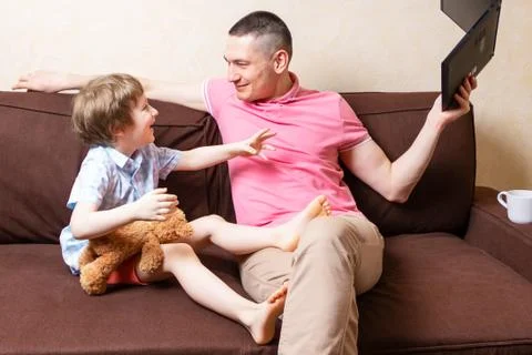 Funny young father sit on computer laptop fool around with cute kid son have  Stock Photos