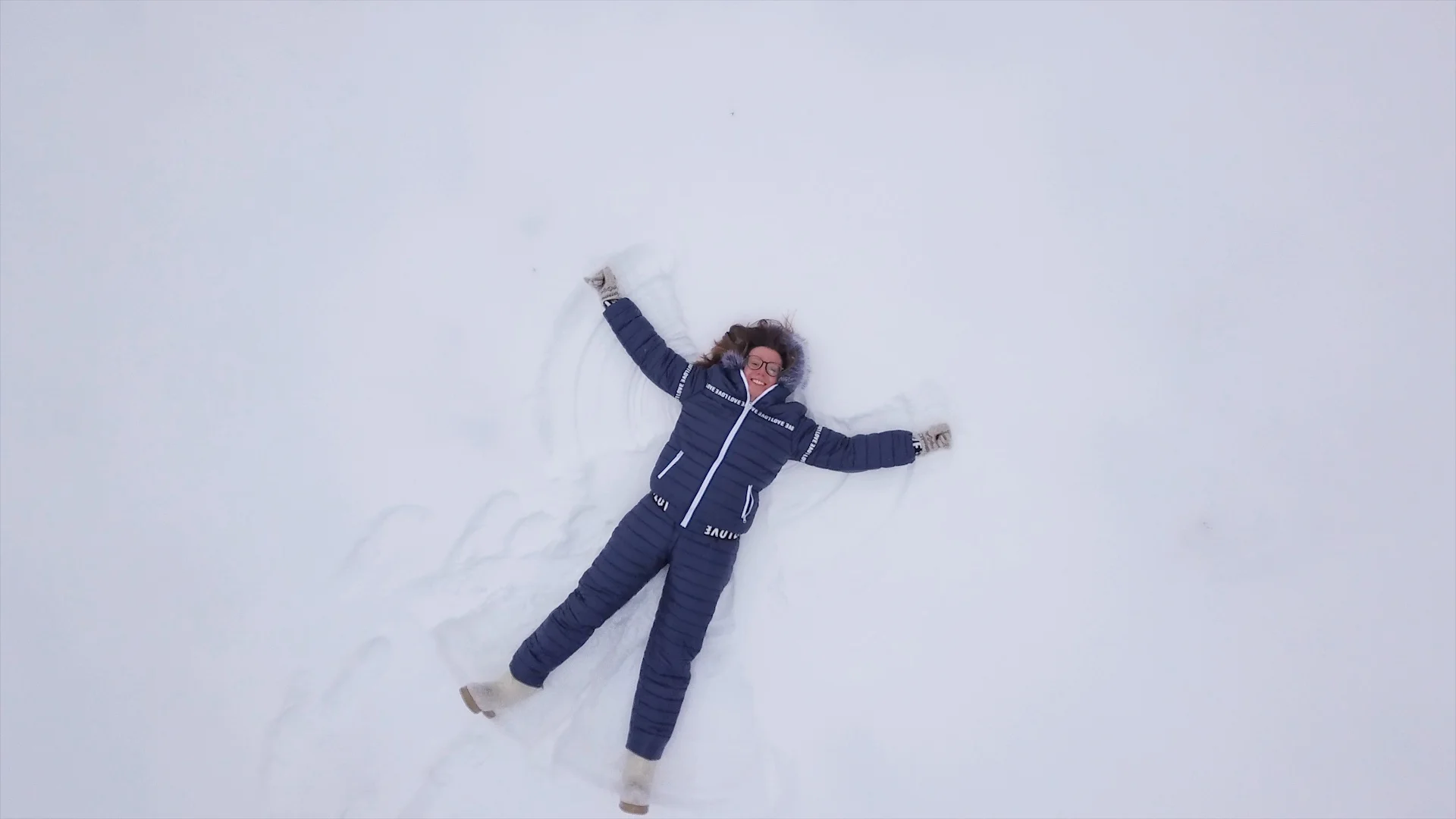 Funny young girl making snow angel