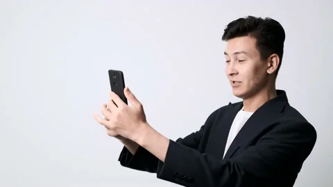 A funny young guy in a jacket and with a cell phone in his hands is talking Stockbeeldmateriaal 162191882