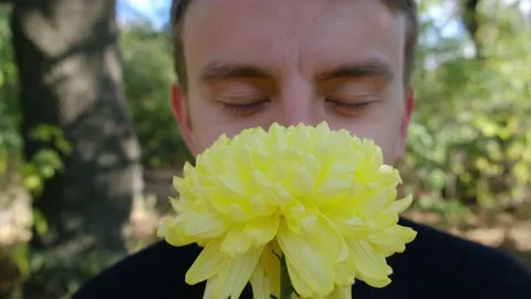 Funny young guy smelling a flower, closeup Stock-Footage 143783932