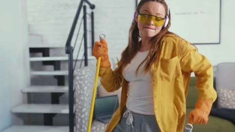 Funny young lady is having fun during clean-up singing and dancing with mop Stock Footage 132532629
