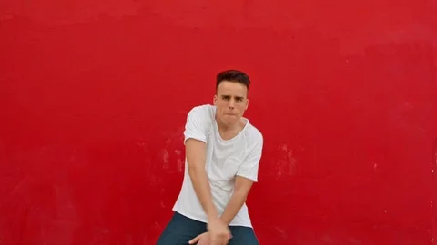 Funny young man dancing with a red wall on the background. Vidéo 120515196