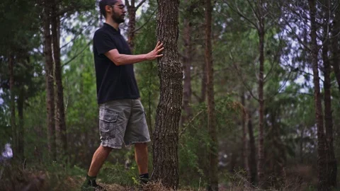 Funny Young Man magically disappears behind a tree and then appears again fro Stock Footage 89984386