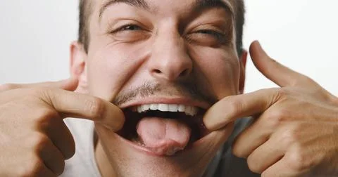 Funny young man with mustache pulling a silly face and sticking out his ton.. Stock Photos