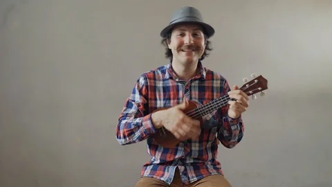 Funny young man playing a ukulele or toy guitar - isolated on white background Stock Footage 123611703