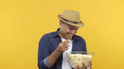 A funny young man put on hat eats popcorn while watching something comedy isolat Stock Footage 144662908