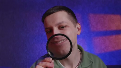 Funny young man smiling with enlarged mouth through magnifying glass Stock Footage 333756954