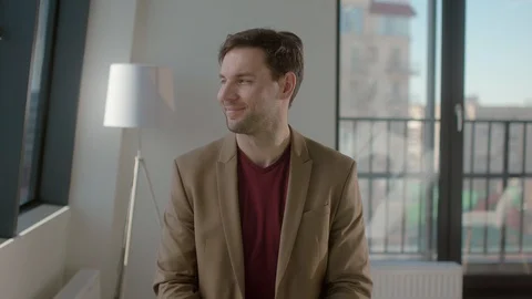 Funny young positive man is sitting in his office and looking at the camera Stock Footage 128451833
