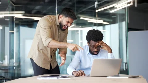 Furious boss standing in modern office yelling at employee sitting at desk Stock Footage 336558311