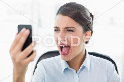 Furious classy brown haired businesswoman yelling at her mobile phone Stock Photos
