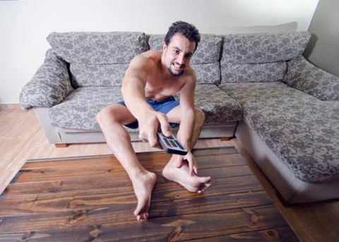 Furious man hate expression change tv channels with remote control Stock Photos