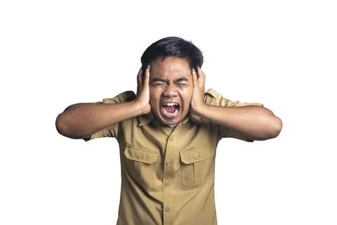Furious or stressed young man in a khaki uniform shirt covering his ears wi.. Stock Photos