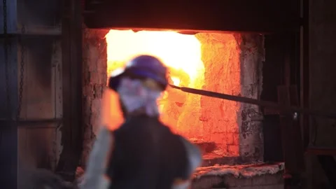 Furnace of casting with high degree Celsius temperature where operator pulling Stock Footage 303477545