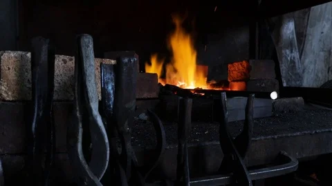 The furnace in the forge burns a flame in the foreground tongs Stock Footage 120112737