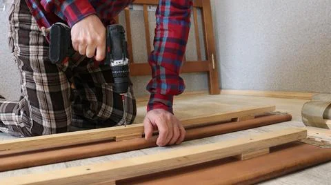 A furniture assembler assembles a bed in a room Stock Photos