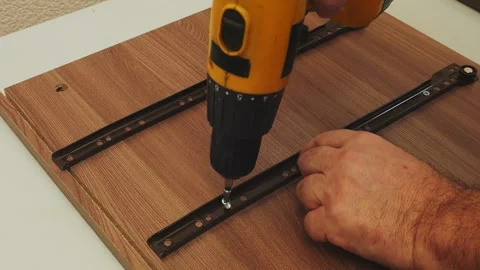 A furniture assembler screws drawer strips into place using a screwdriver. .. Vidéo 329438565