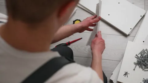 The furniture assembler studies the instructions for assembling furniture. The Stock Footage 240328642