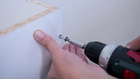 A furniture assembler uses a screwdriver to assemble a cabinet Stock Footage 302285142