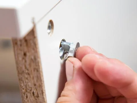 Furniture assembly concept. guy assembles wardrobe close up Stock Photos
