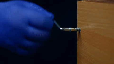 Furniture assembly. hand with a hex key tightening a screw on furniture Stock Footage 303112390