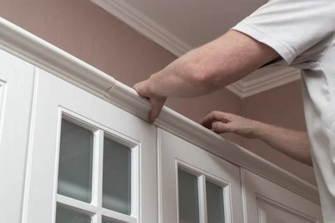 Furniture assembly. A man assembles a kitchen set, attaches stucco molding to Stock Photos