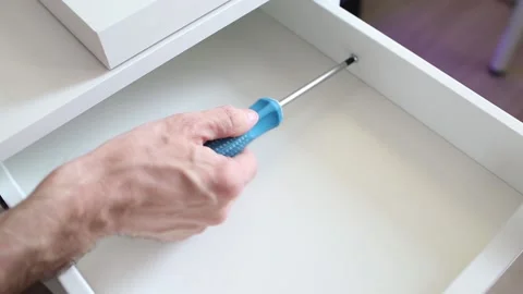 Furniture assembly process. Master assembles the bedside table. The worker uses Stock Footage 154081928