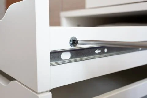 Furniture assembly process. Master assembles the bedside table. The worker uses Stock Photos