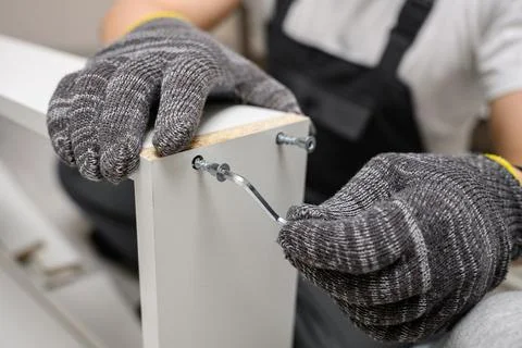 Furniture assembly process using hex key close up. Professional handyman or DIY Photos