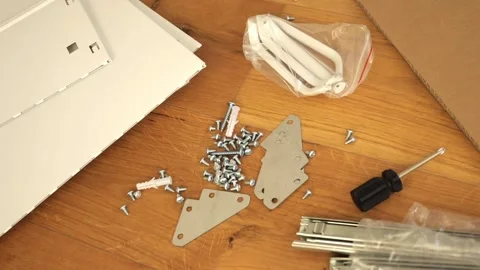Furniture assembly tools and hardware laid out on wooden floor Stock Footage 319406141