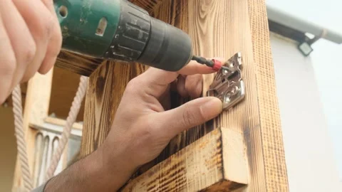 Furniture assembly worker s hands using electric screwdriver to attach door hing Stock Footage 332875378