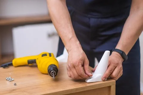 Furniture fixing process handyman assembling wooden cabinet with electric Stock Photos