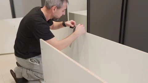 A furniture maker assembles a cabinet at the customer's home. Assembling Video stock 267688185