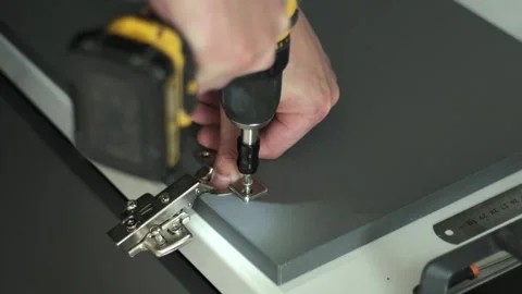 Furniture maker uses a screwdriver to attach hinges to a door of a cabinet Video stock 200812902