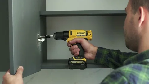 Furniture maker uses a screwdriver to attach hinges to a door of a cabinet Stock Footage 201326030