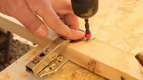 Furniture maker using electric screwdriver to attach door hinge to new cabinet.  Stock Footage 332875303