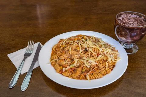 Fusilli pasta dish with dessert on table 스톡 사진