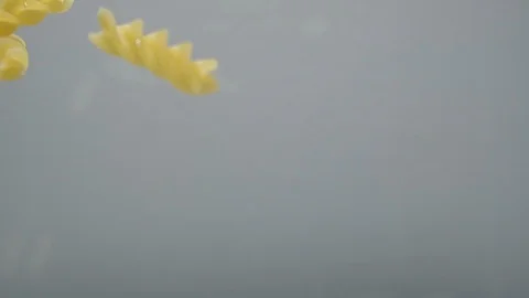 Fusilli pasta falls into the water, close-up, slow motion. Cooking the pasta. Stock Footage 124306012