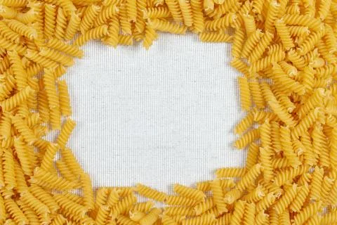 Fusilli pasta making a frame on rustic linen fabric Stock Photos