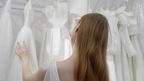 Future bride thoughtfully choosing wedding dress at clothing store Stock Footage 304541935