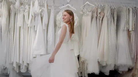 Future bride wearing elegant white wedding dress posing in bridal shop Stock Footage 301328903