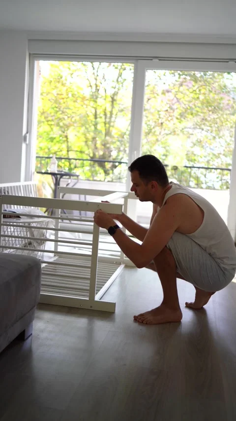 Future father assembling a white crib in a minimalist nursery room Stock Footage 329486403