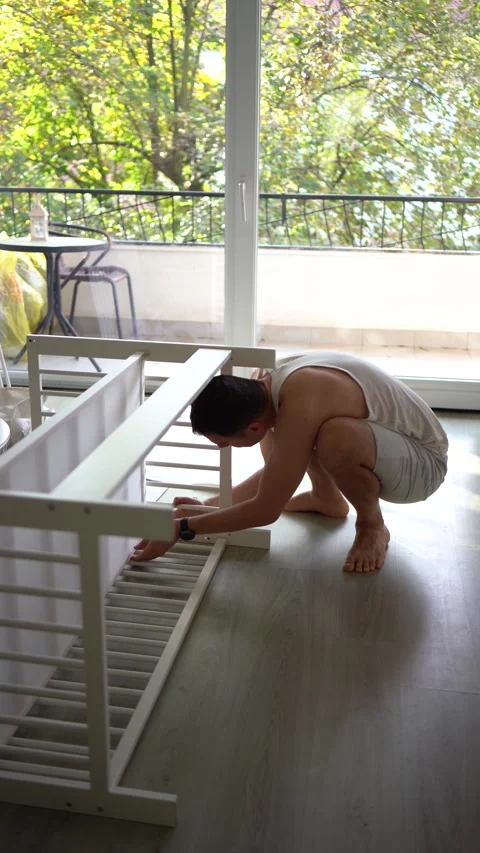 Future father assembling a white crib in a minimalist nursery room Stock Footage 329486408
