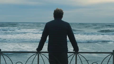 Future Horizons: Man at Seafront Pondering Uncertain Future Stock Footage 261277976