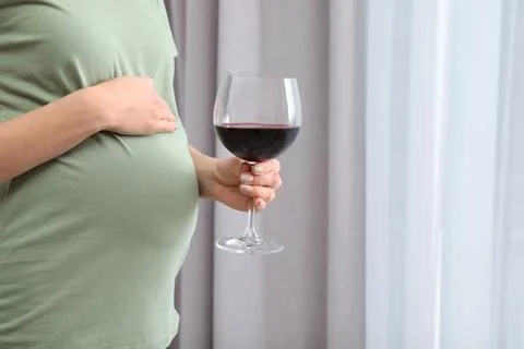 Future mother with glass of wine indoors, closeup. Alcohol abuse during pregn Stock Photos