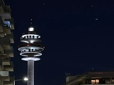 Futuristic communications tower lit up during night in the city, starry night Stock Photos