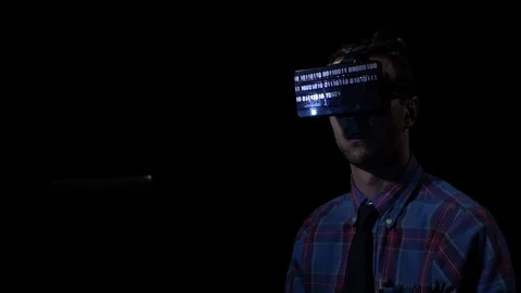 Futuristic computer programmer worker sitting in a dark room and trying VR gl Stock Footage 86434550