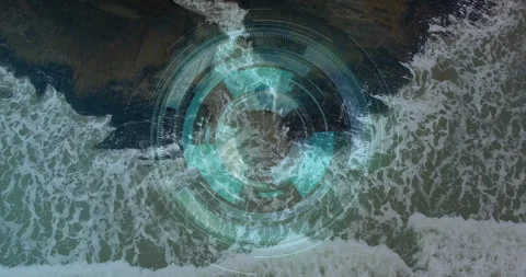 Futuristic digital HUD overlay floating above rocky coastline showing data rings 動画素材 307431600