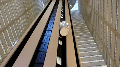 Futuristic glass elevator rockets up a skyscraper atrium 動画素材 165548504
